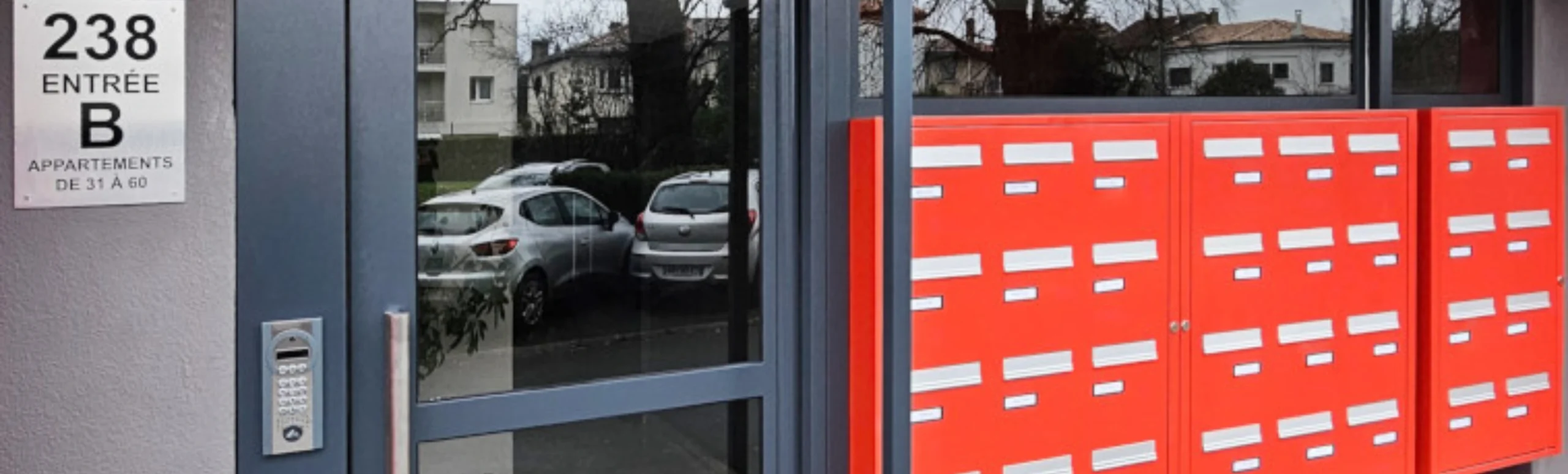 Entrée d'un immeuble avec la porte d'entrée et les boites aux lettres