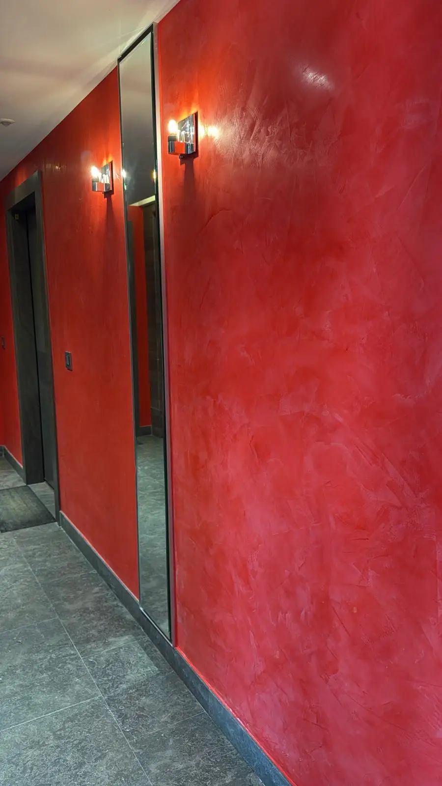 Mur avec une peinture à effet rouge dans un couloir d'un immeuble.